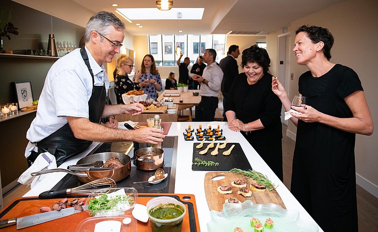 Chef and guests enjoy conversation as food is prepared